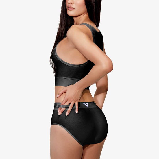 Model wearing Women’s black rib-knit underwear, Core Rib Brief, back view with three-quarter turn pose — Color: Black