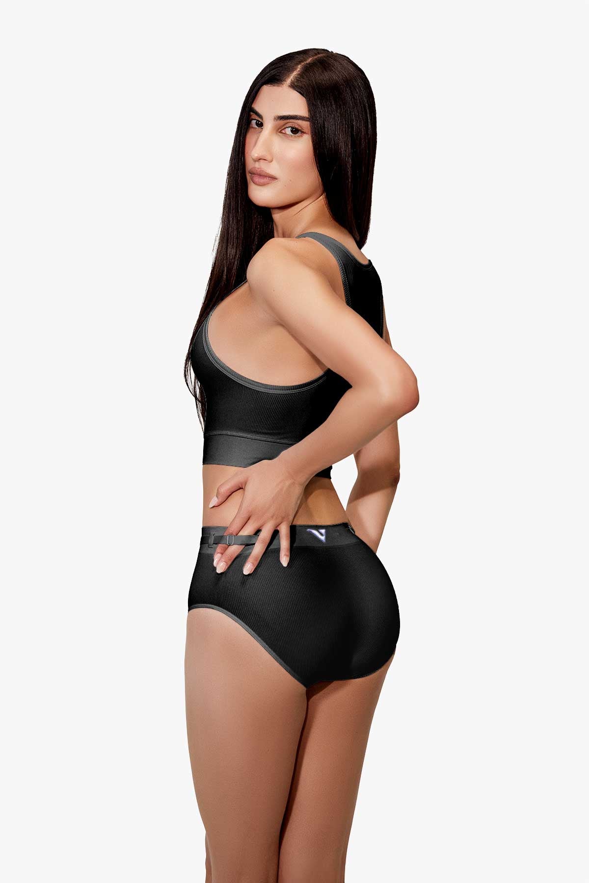 Model wearing Women’s black rib-knit underwear, Core Rib Brief, back view with three-quarter turn pose — Color: Black
